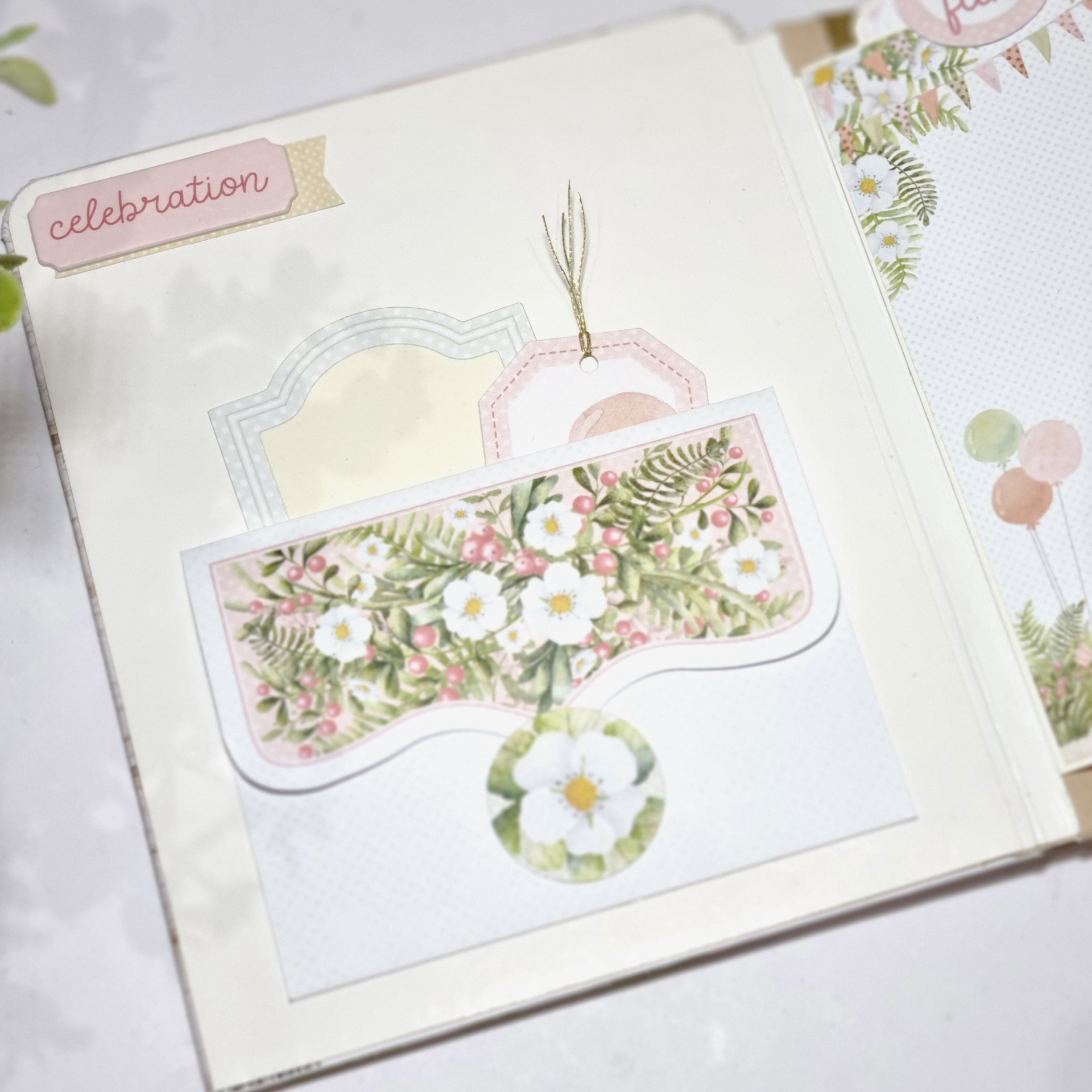 Álbum de scrapbook com bolso decorativo floral e etiquetas com molduras coloridas.
