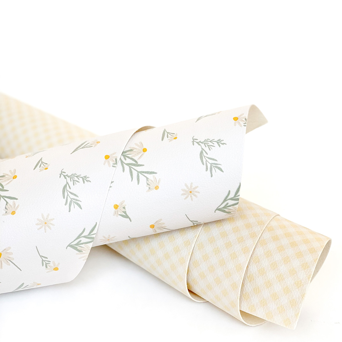 Rolos de papel decorativo com padrões floral e xadrez em tons claros