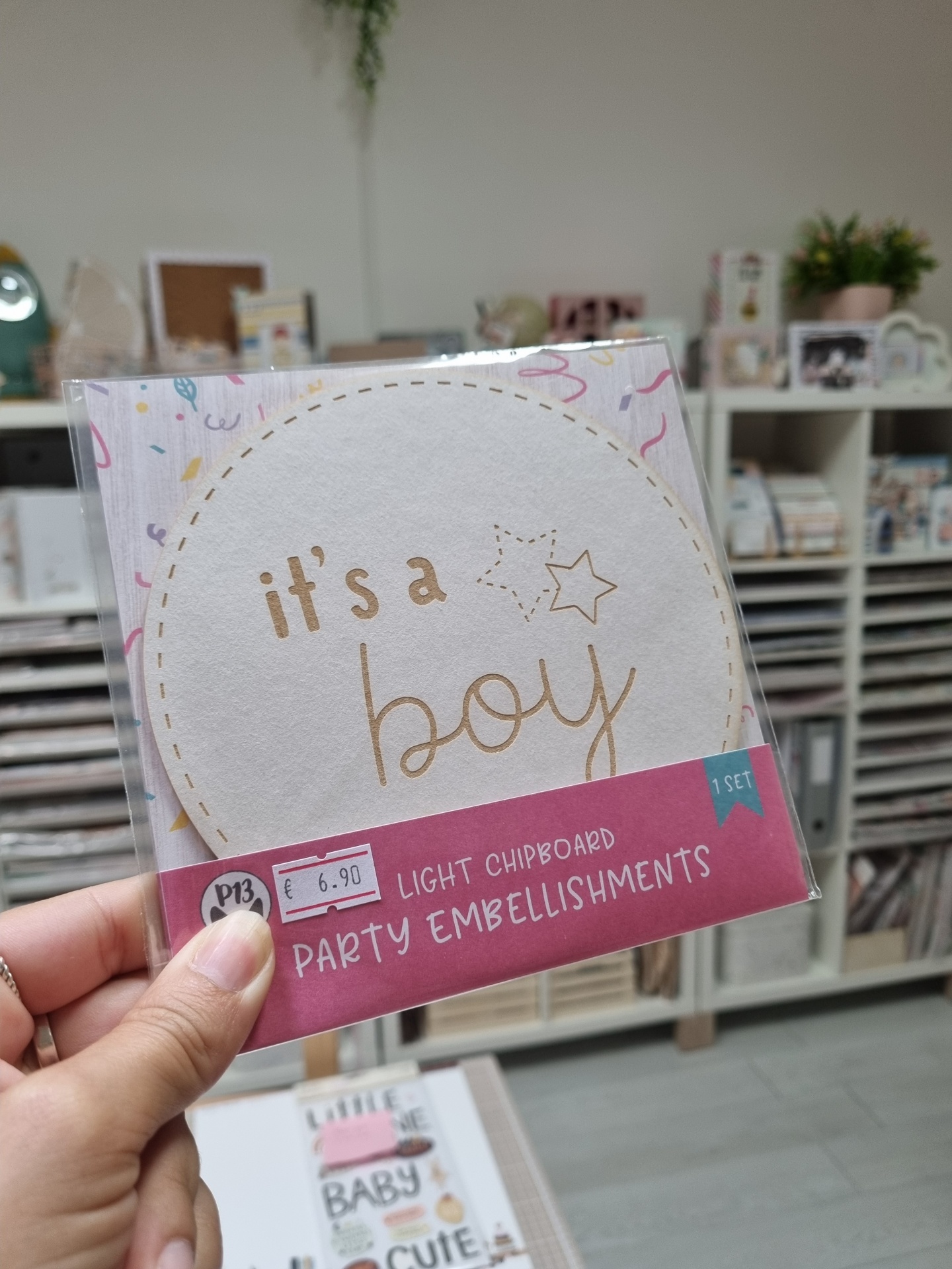 Chipboard círculo com texto its a boy em embalagem plástica com etiqueta rosa e preço €6.90