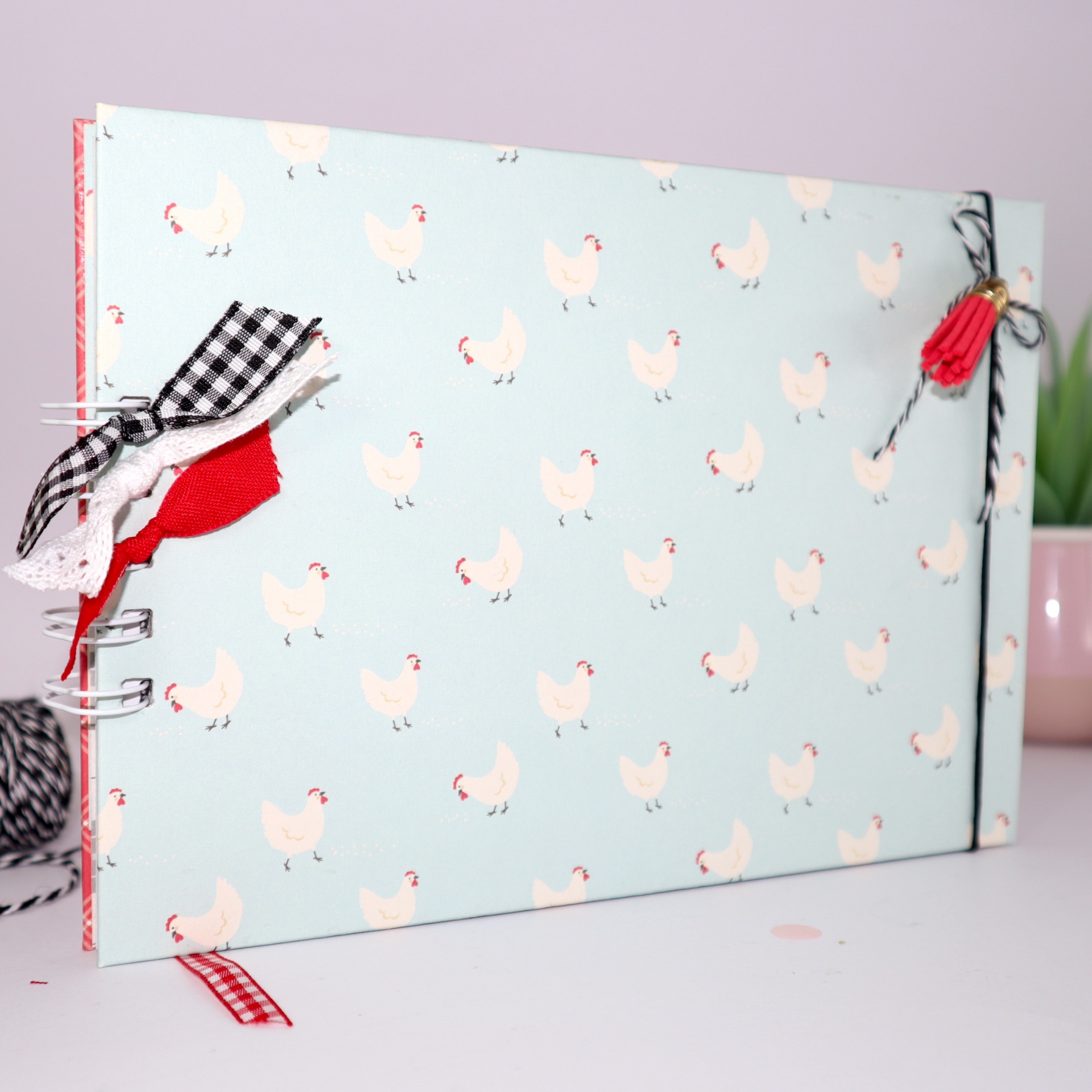 Caderno azul com padrão de galinhas brancas e decorações de tecido colorido