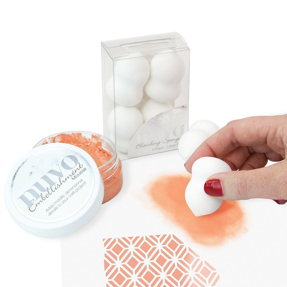 Esponjas de maquilhagem brancas, embalagem transparente, frasco com pó salmão e mão a aplicar pó numa superfície padrão