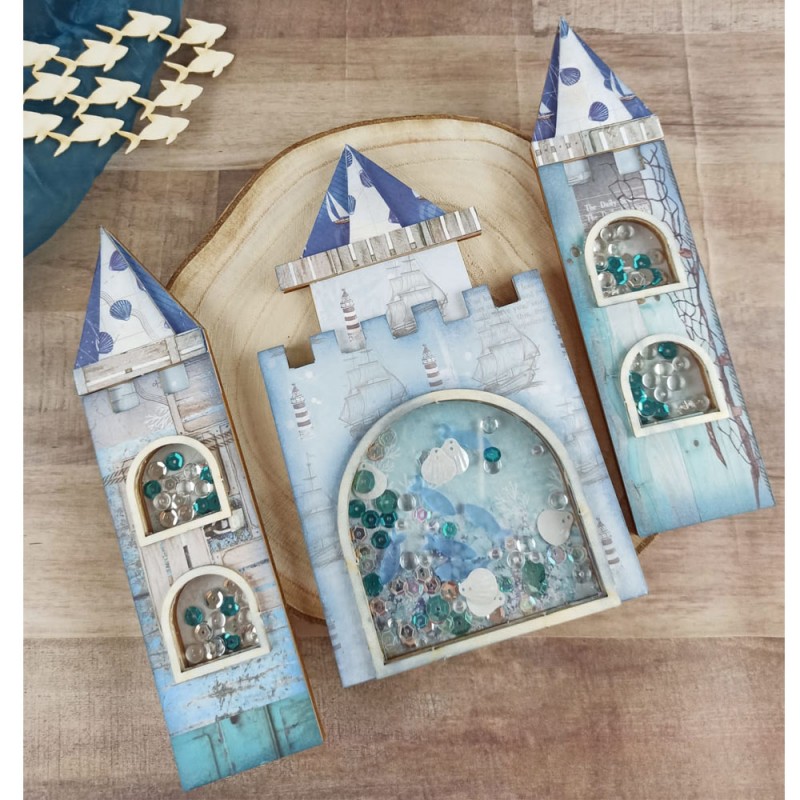 Três castelos decorativos em madeira com detalhes azuis e brancos e partículas dentro de compartimentos de vidro.