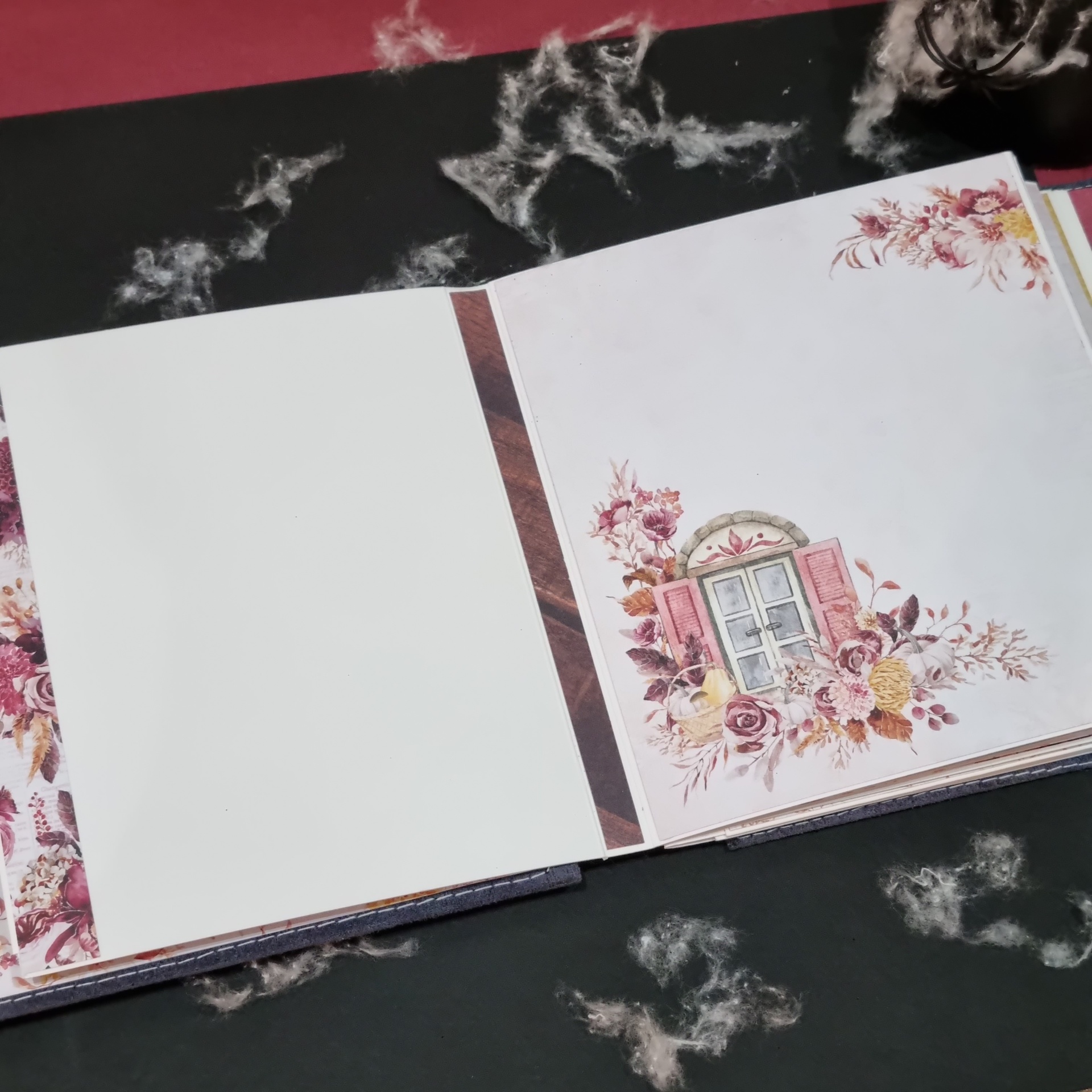 Livro decorativo aberto com ilustrações florais e janela com persianas cor de rosa.