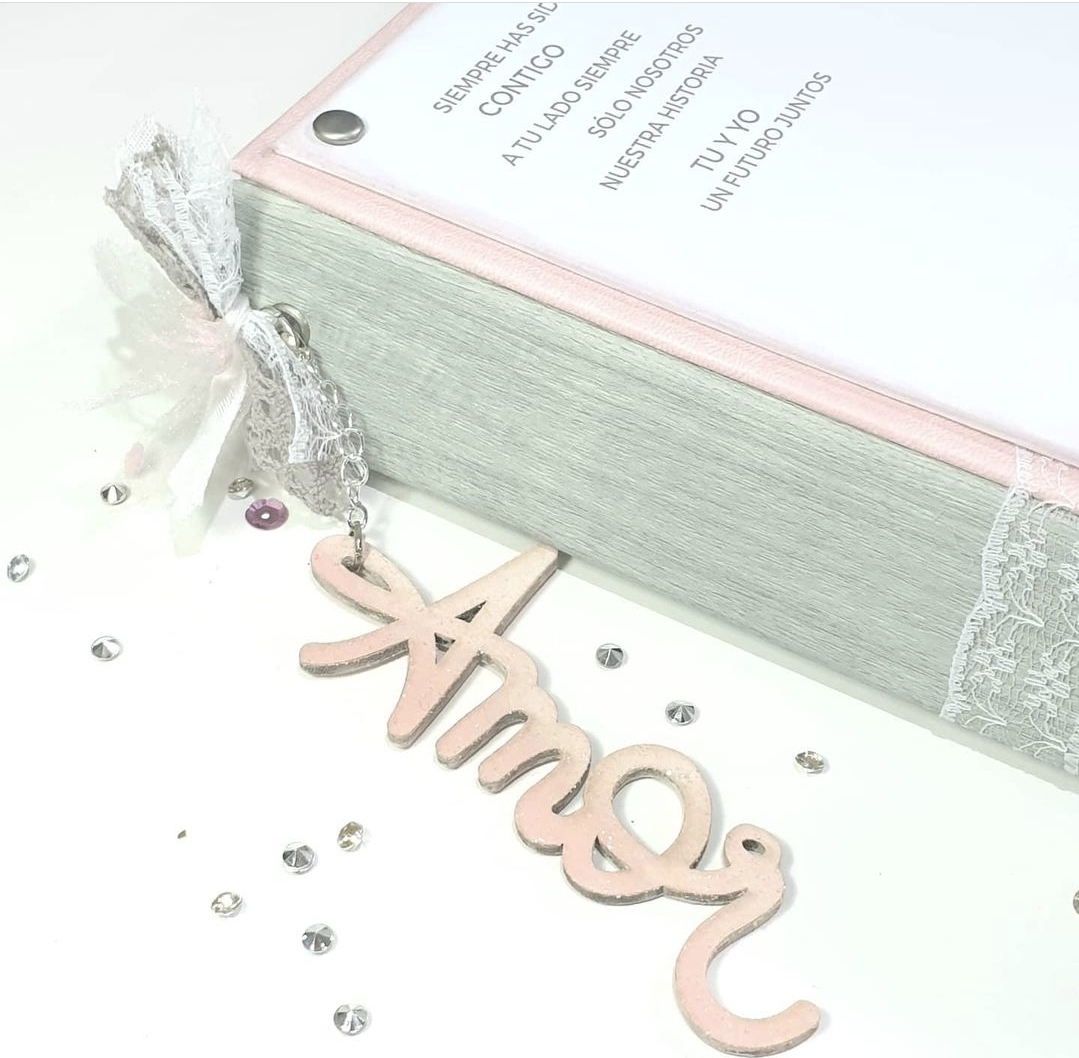 Livro com capa cinza e fita de renda branca e pendente de madeira com palavra 'Amor'