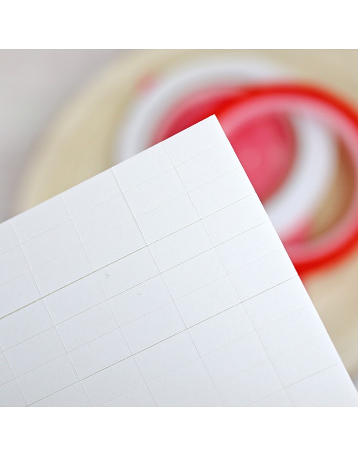 Folha branca com quadrículas e fitas adesivas desfocadas ao fundo