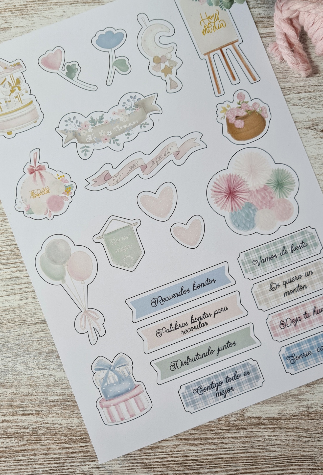 Folha de adesivos coloridos com desenhos e frases em espanhol sobre fundo de madeira