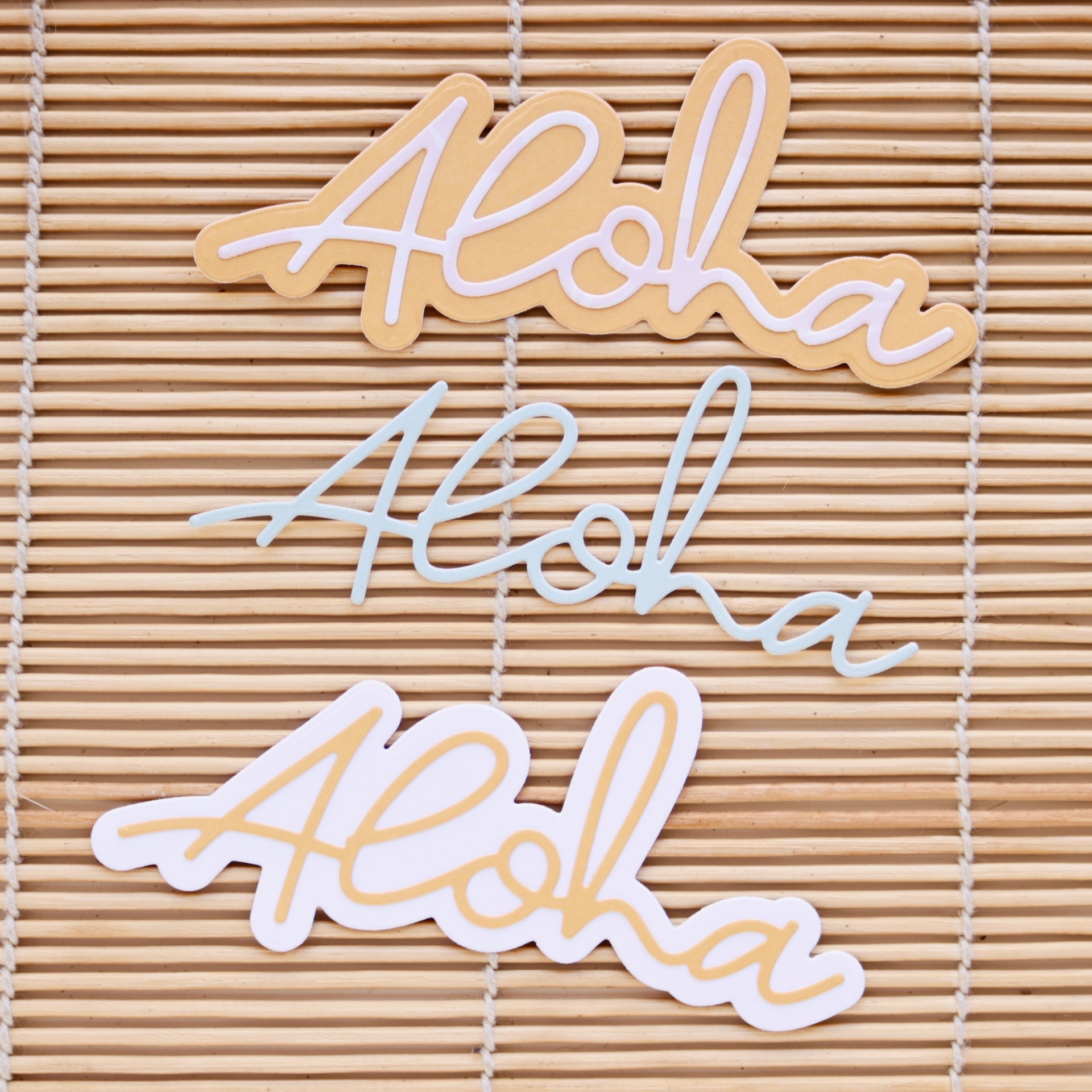 Recortes com a palavra Aloha em amarelo e branco sobre ripas de madeira clara