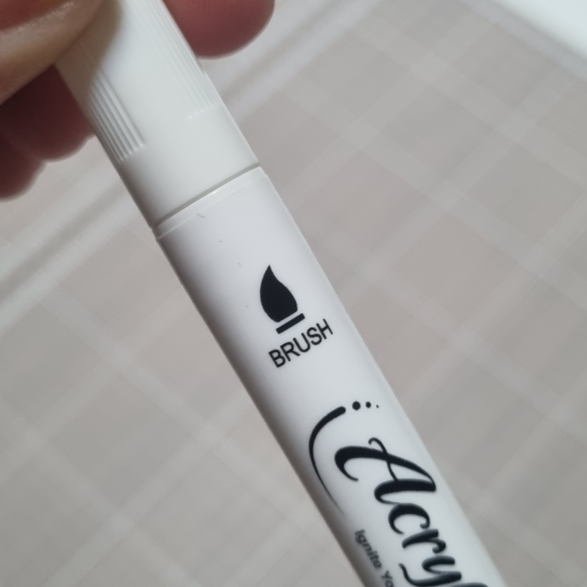 Marcador branco com texto BRUSH e ícone de pincel, sobre fundo branco quadriculado.