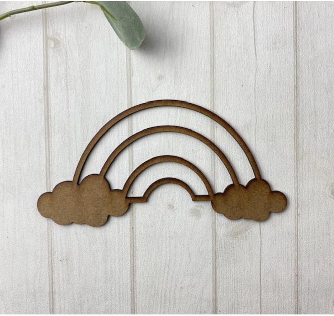 Decoração em MDF formato arco-íris com nuvens, madeira castanha, fundo madeira branca.