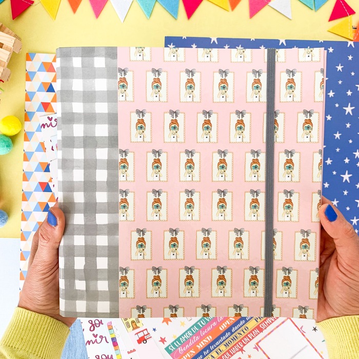 Caderno rosa com padrão de etiquetas com animais e flores, elástico preto vertical