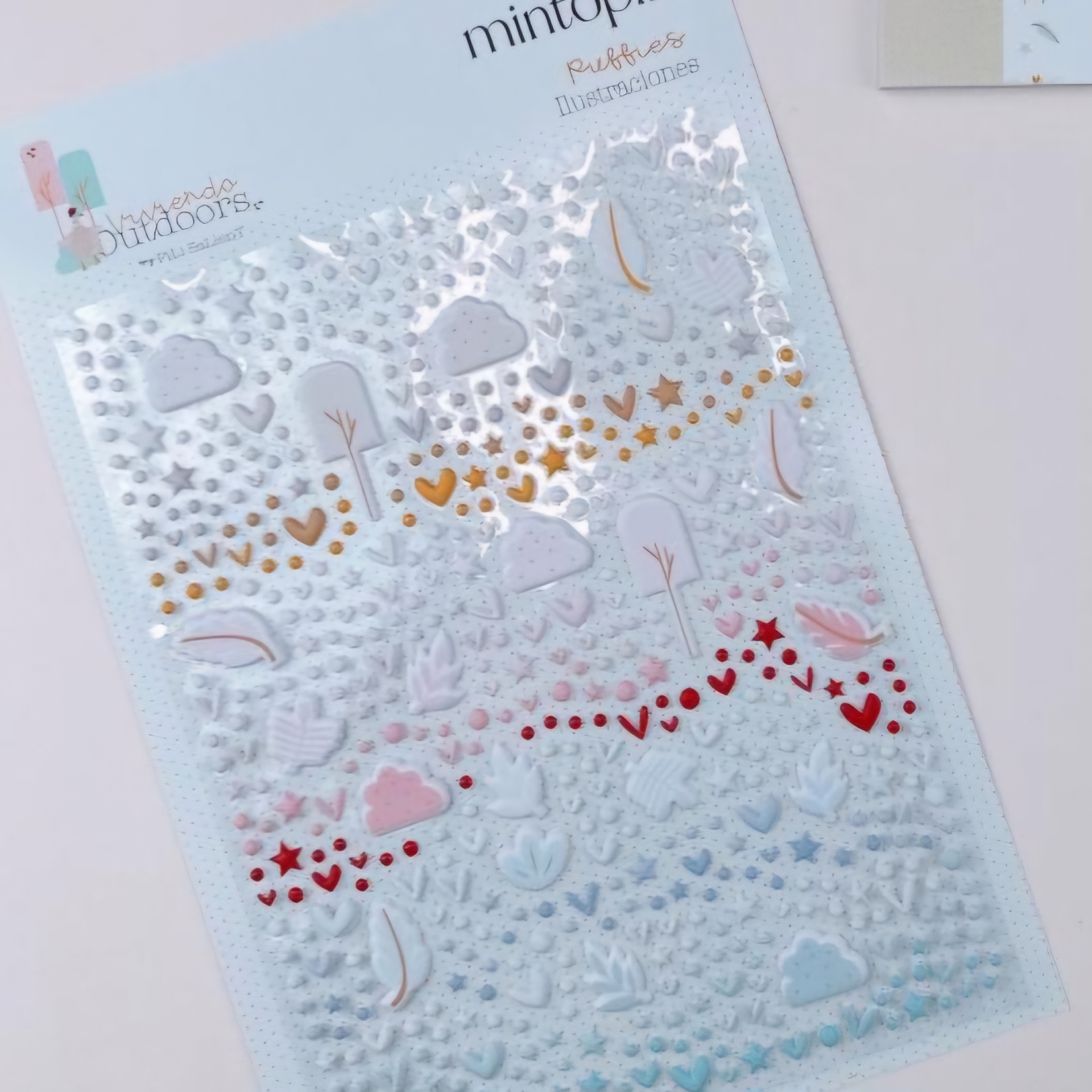 Folha de autocolantes com nuvens, árvores, corações e folhas em várias cores pastel e tons dourados