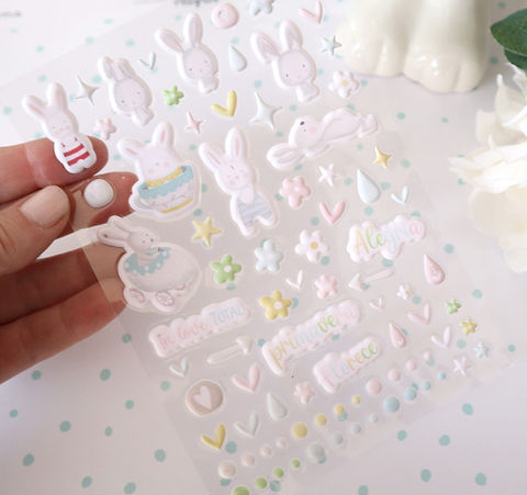 Folha de autocolantes com desenhos de coelhos e elementos decorativos em tons pastel