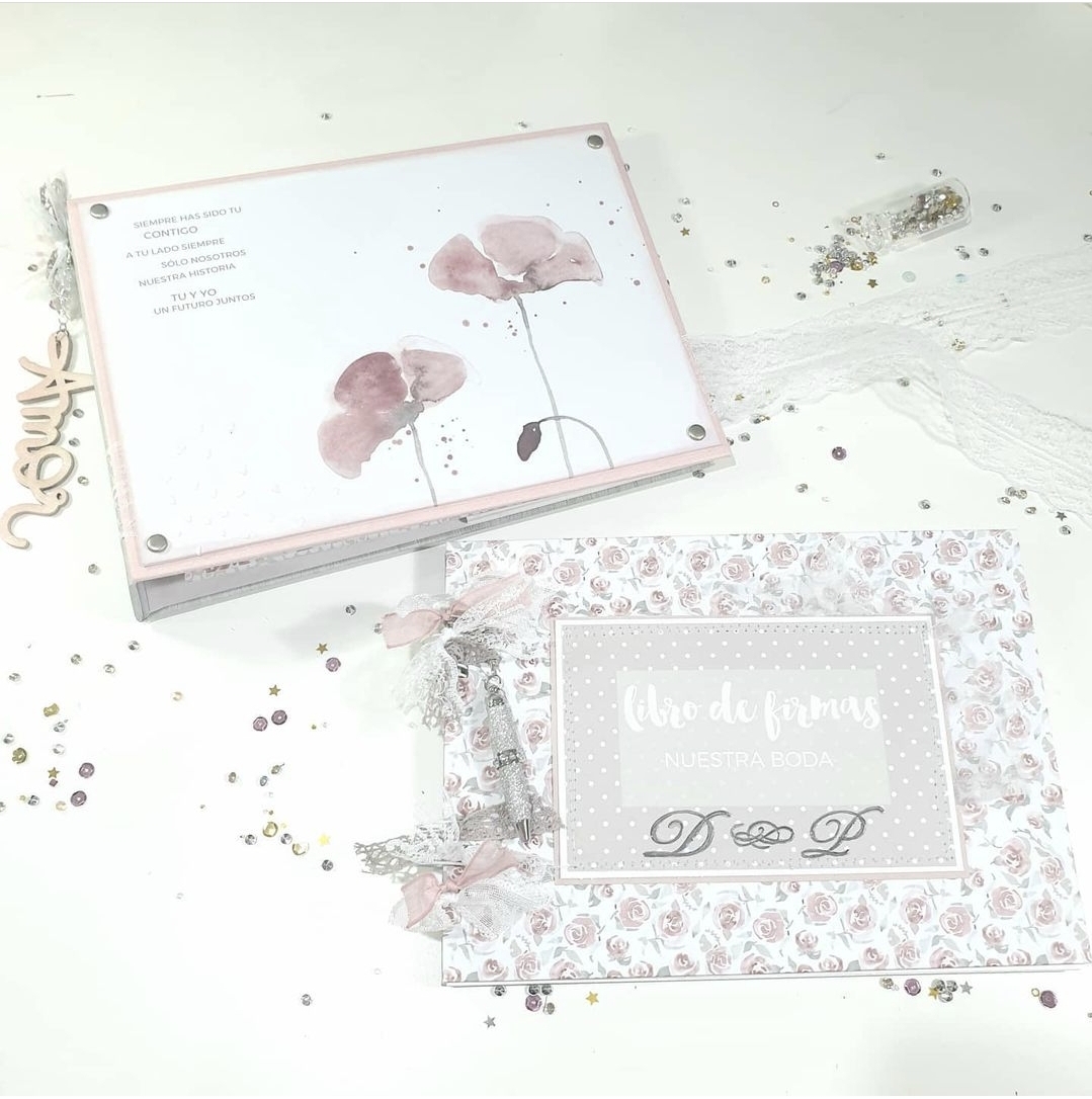 Dois livros de assinaturas decorativos com temas florais e texto em espanhol, sobre superfície branca com lantejoulas.