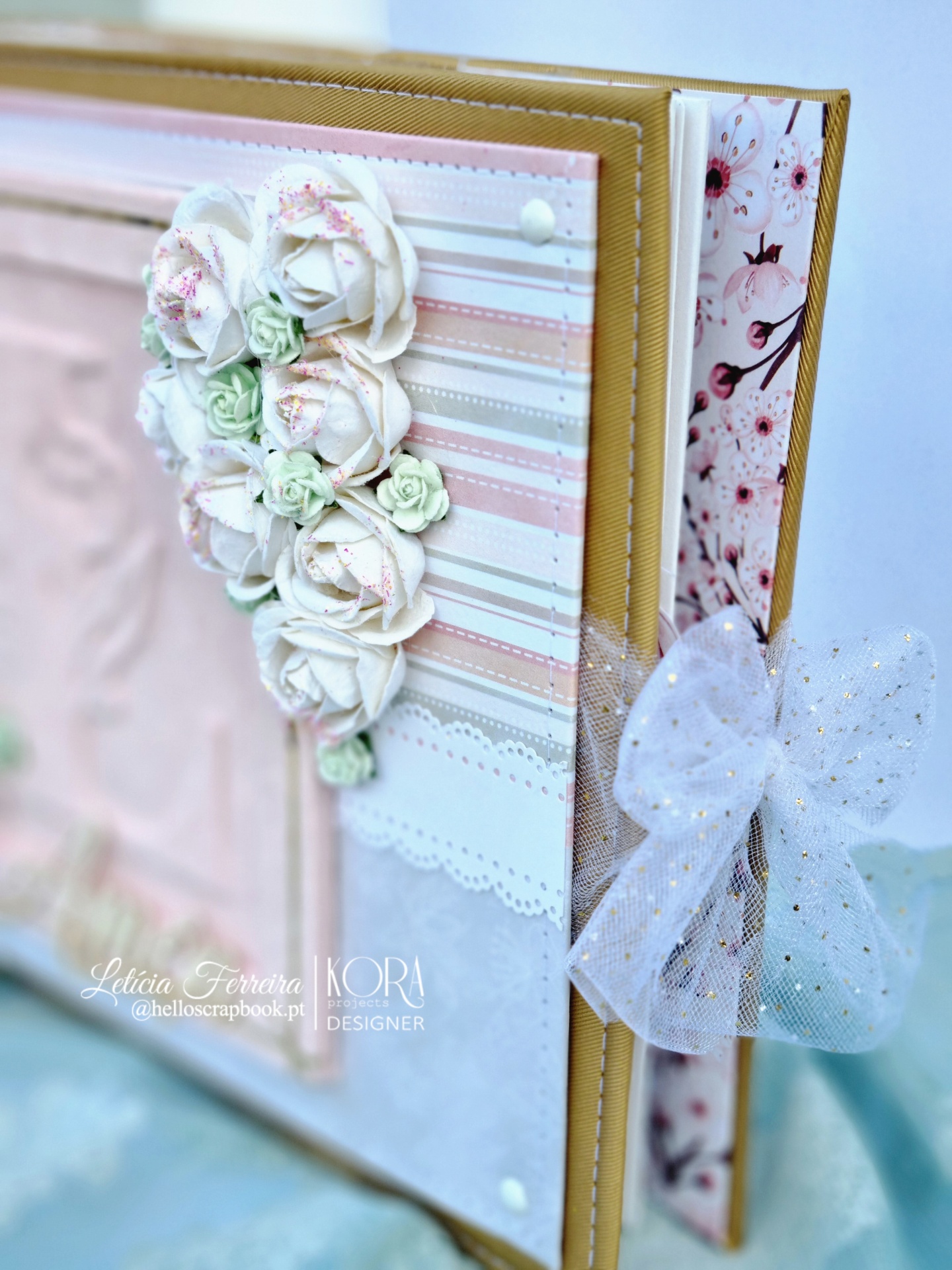 Álbum artesanal com flores de papel e laço de tule branco com pontos dourados