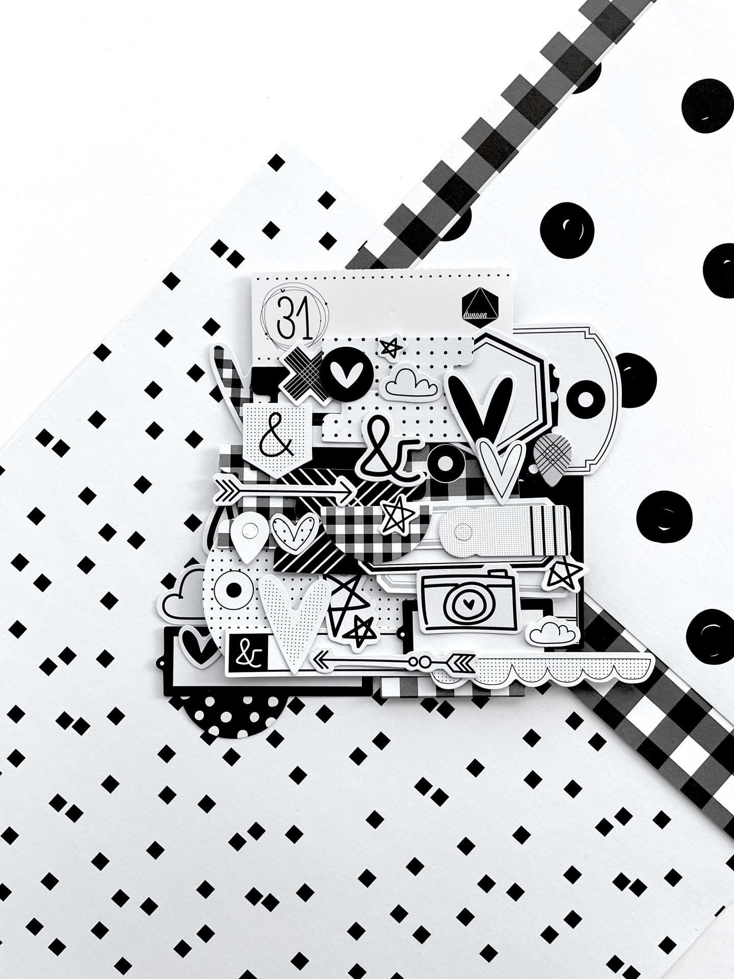 Recortes de papel em preto e branco com vários padrões decorativos sobre fundo preto e branco.