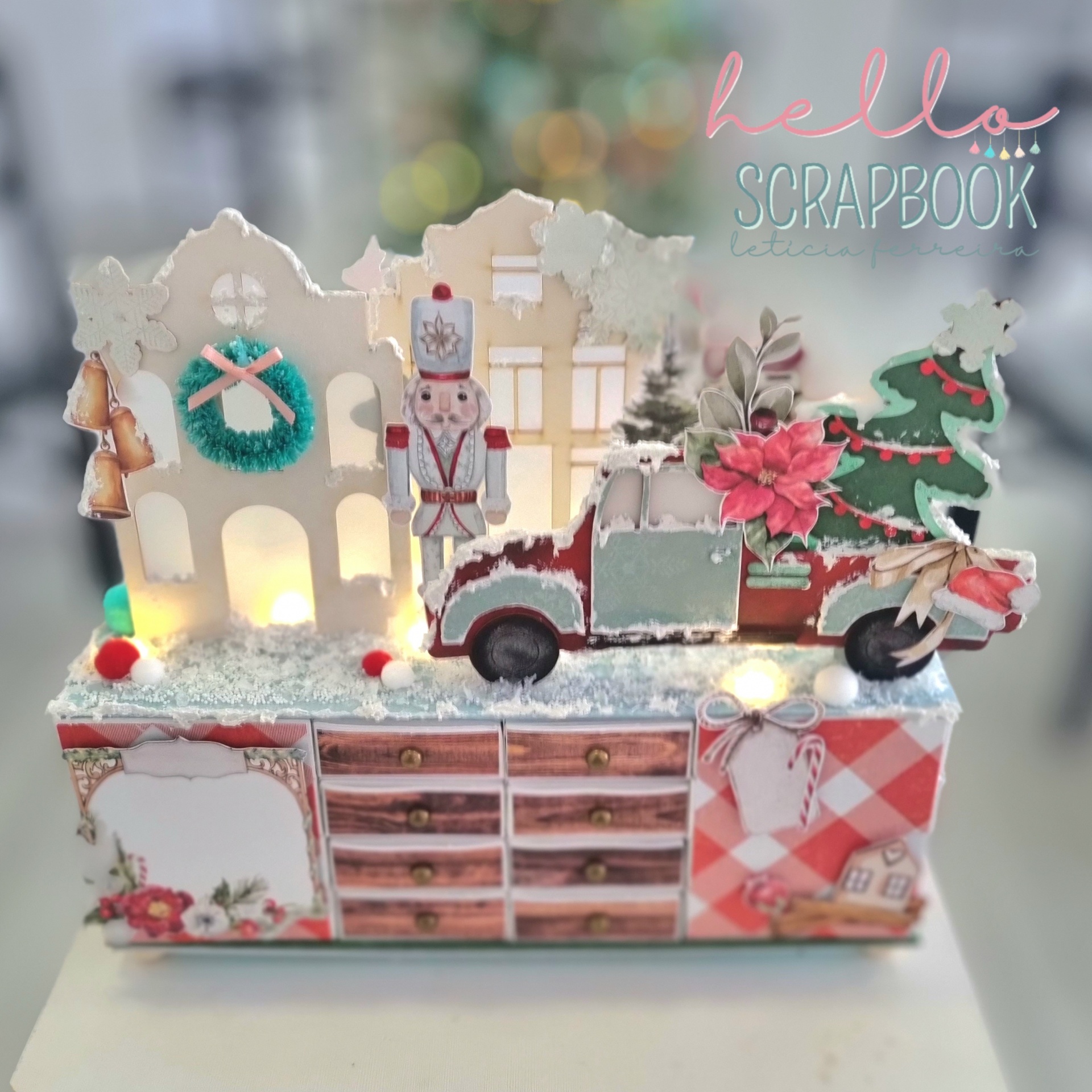 Decoração natalícia com casas, soldado, carro, flores e árvore em cima de caixa decorativa