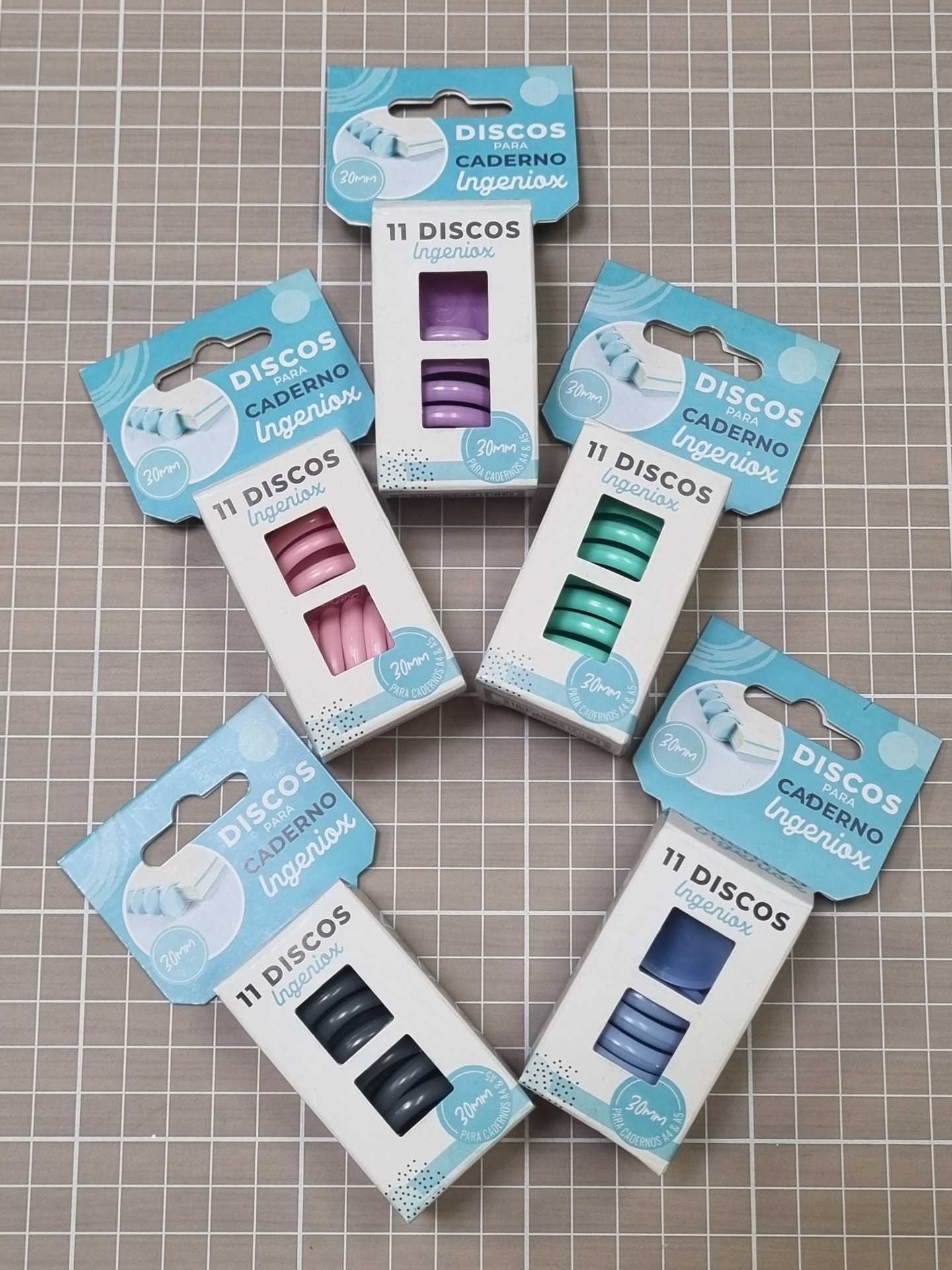 Pacotes coloridos de discos para caderno Ingeniox sobre mesa quadriculada