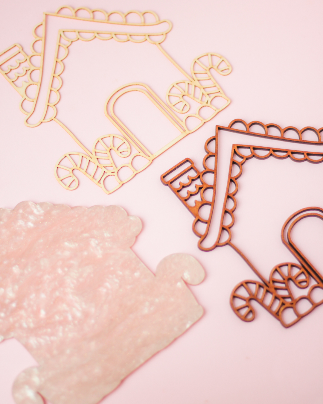 Estruturas em forma de casinha de materiais rosa fosco e arame bege e castanho sobre fundo rosa claro.