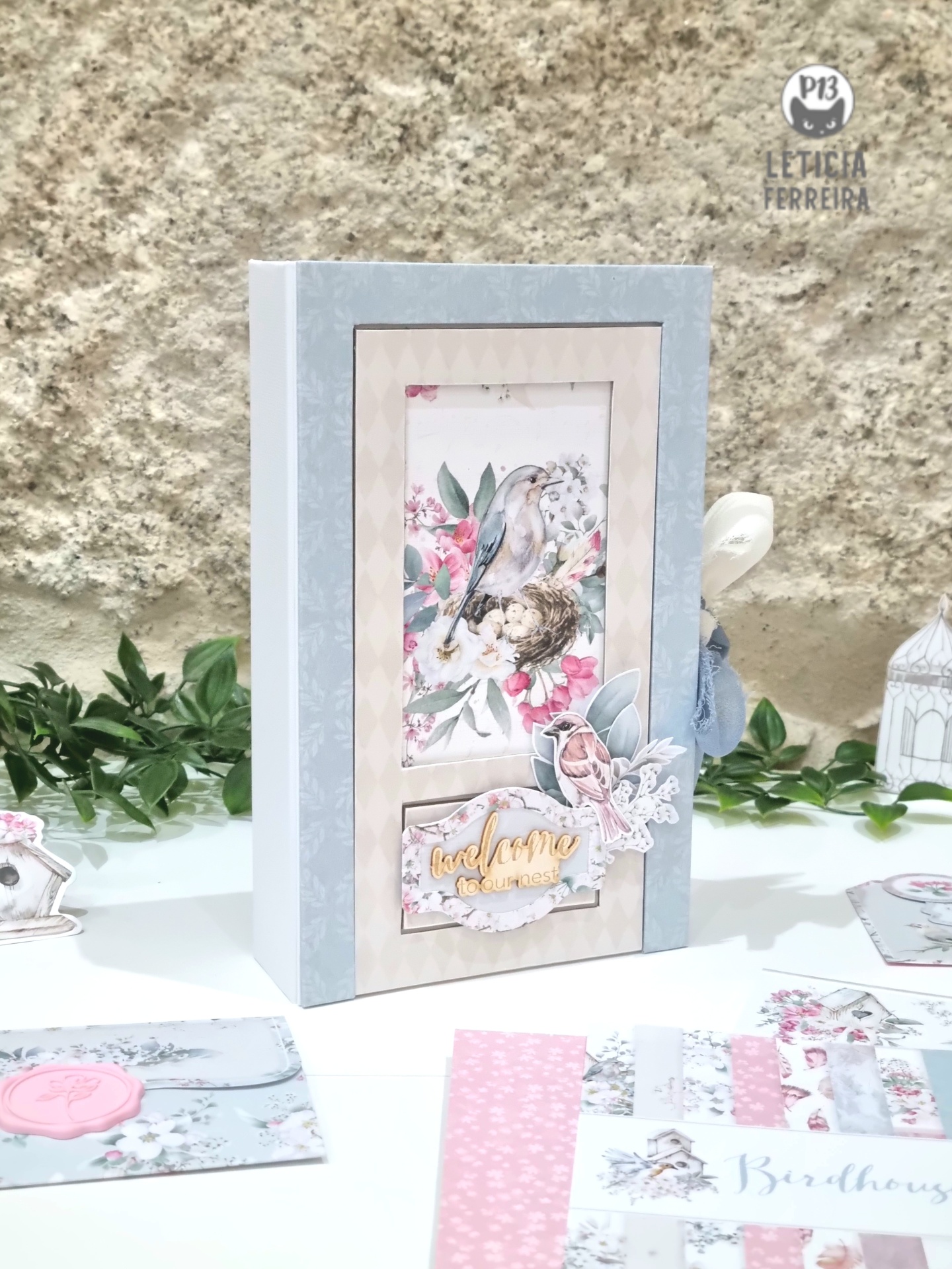 Livro ou caixa decorativa com ilustração de pássaro e flores, texto 'love home', fundo cinza e bege