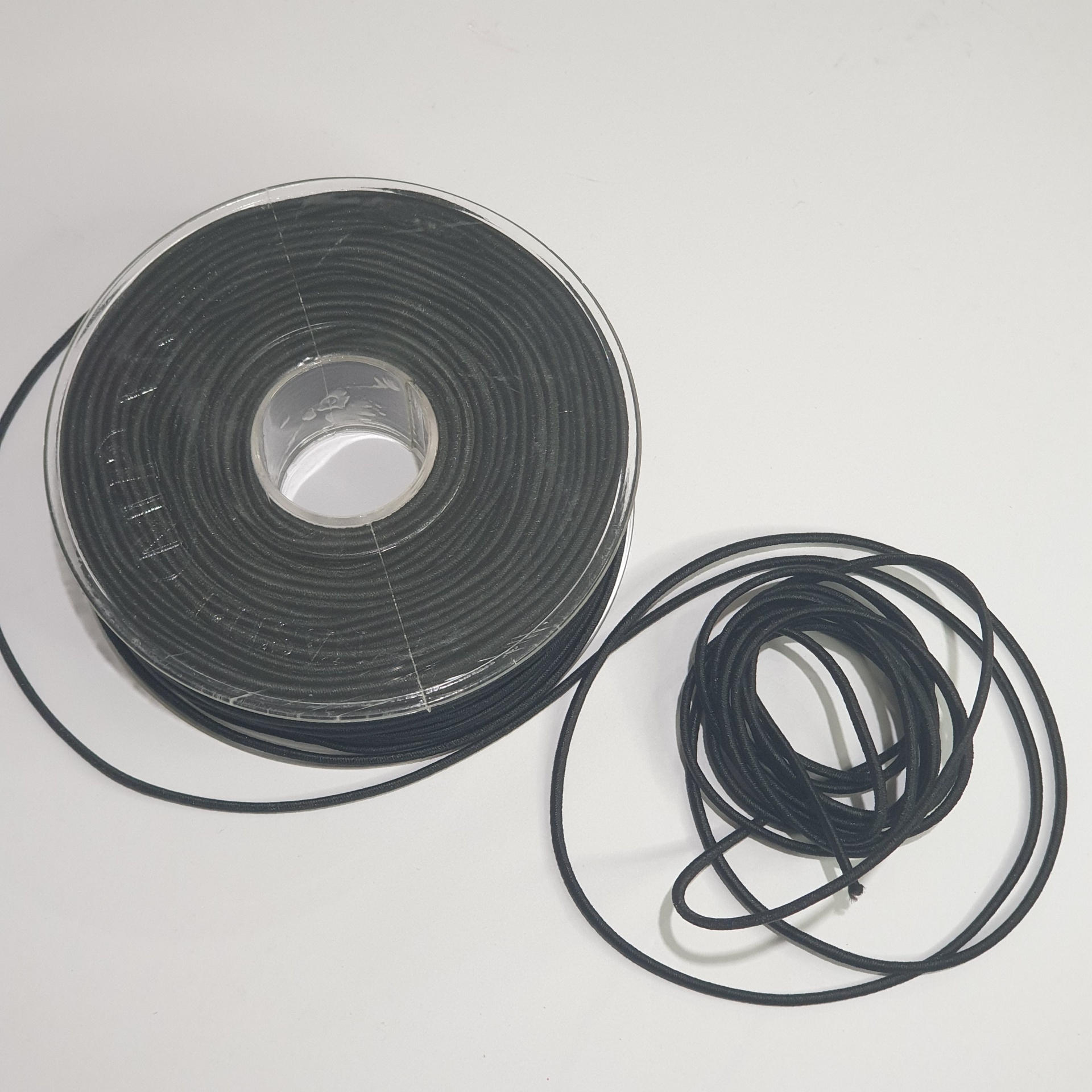 Rolo grande de fio ou cordão preto com um pedaço solto ao lado