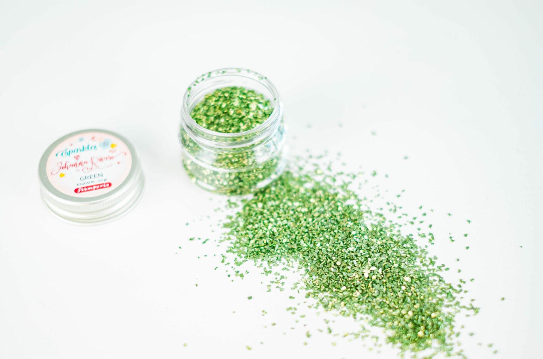 Frasco aberto de glitter verde com tampa ao lado sobre fundo branco