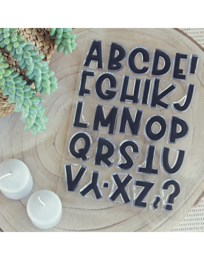 Carimbos alfabéticos pretos em base transparente sobre madeira com velas e plantas suculentas