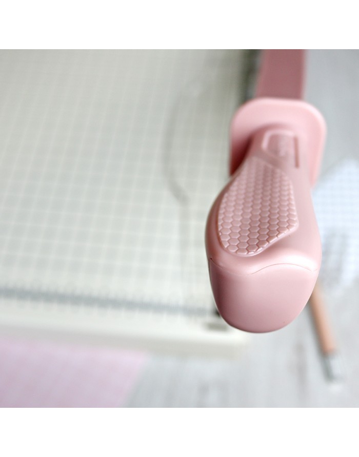 Ferramenta de corte de papel com alça rosa e base branca com grelha