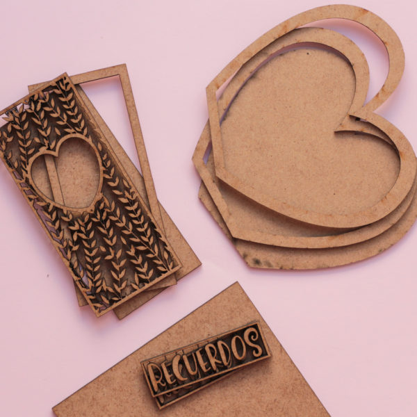 Peças de madeira cortadas a laser com padrão de folhas, corações e texto RECUERDOS