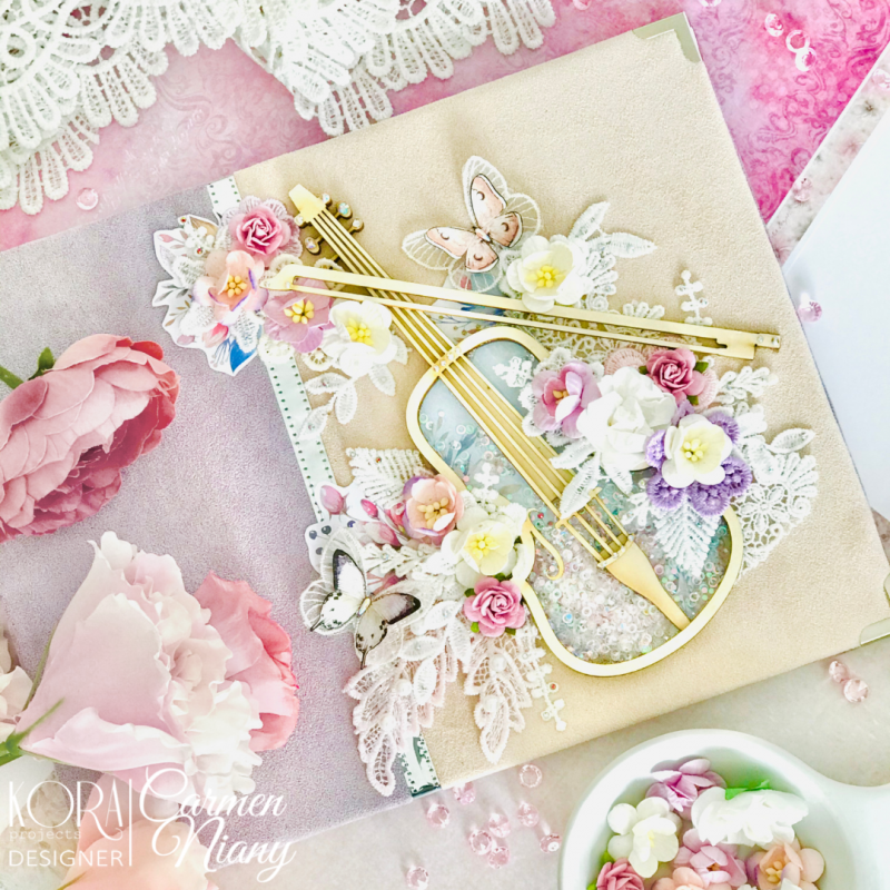 Cartão decorativo com violino dourado, flores artificiais, borboletas e rendas sobre fundo rosa