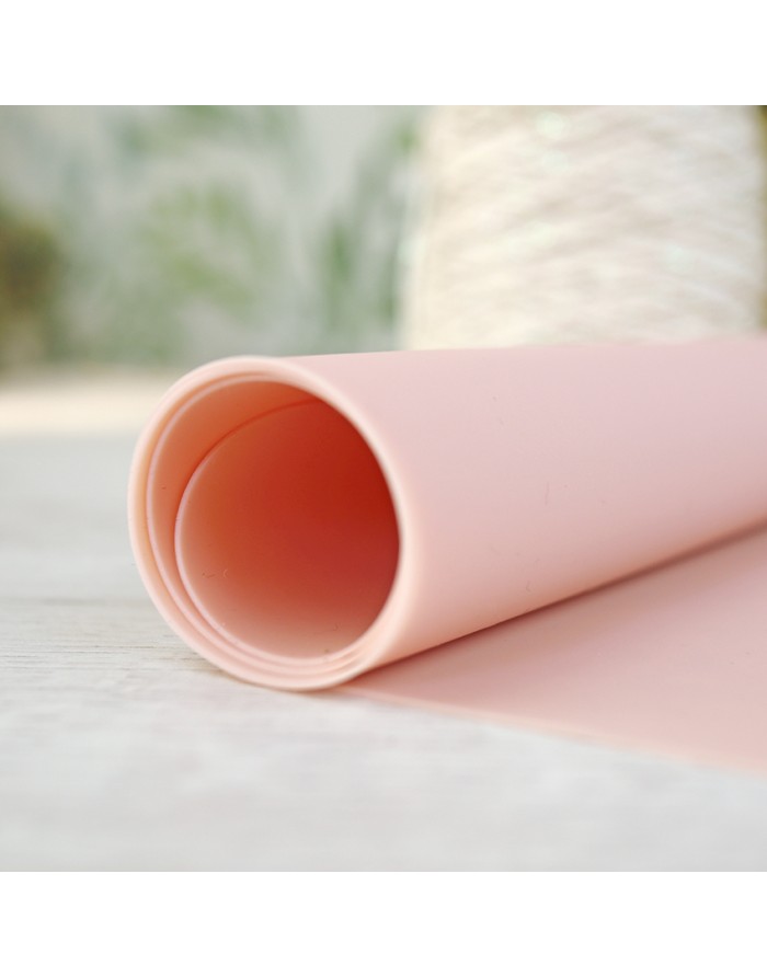 Rolo de material rosa claro e textura lisa em superfície clara