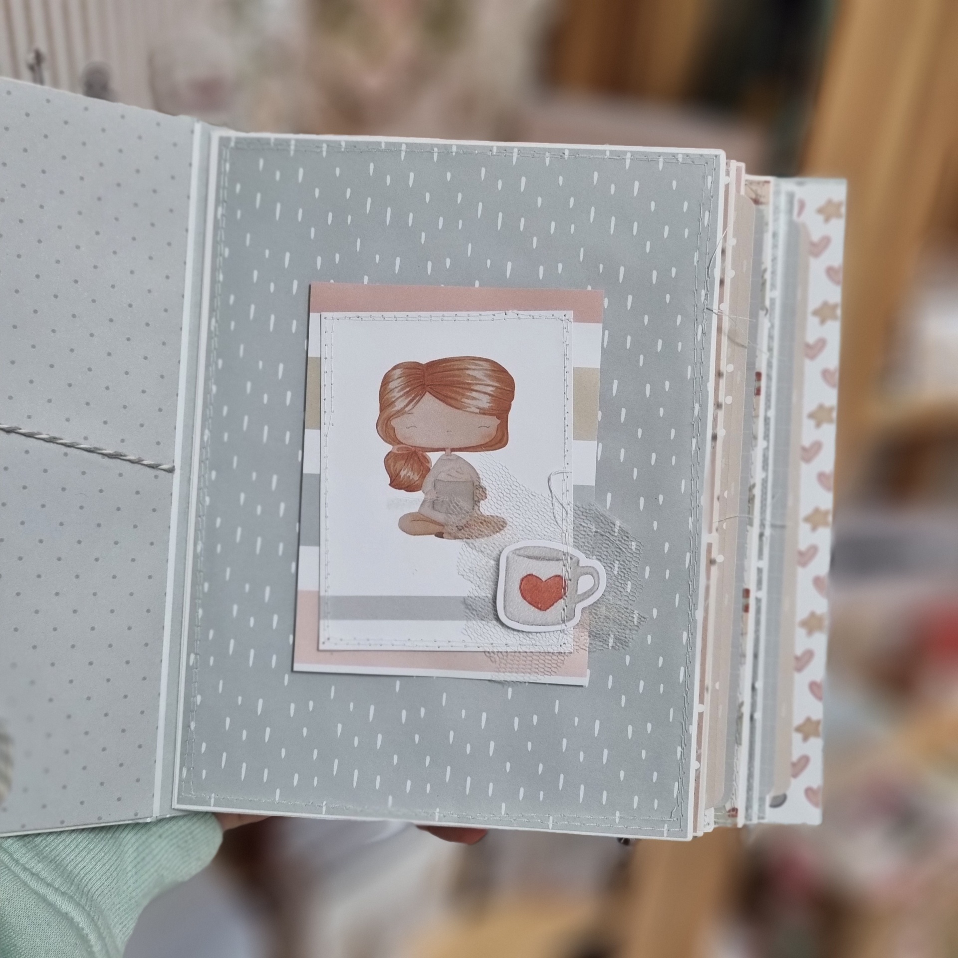 Livro artesanal com ilustração de menina e chávena com coração vermelho