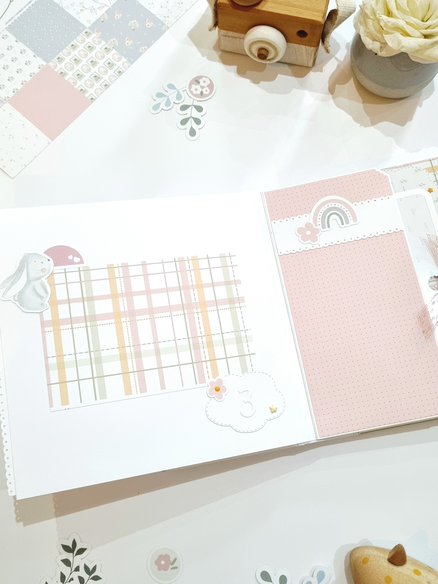 Álbum de recortes com design pastel e elementos decorativos à volta