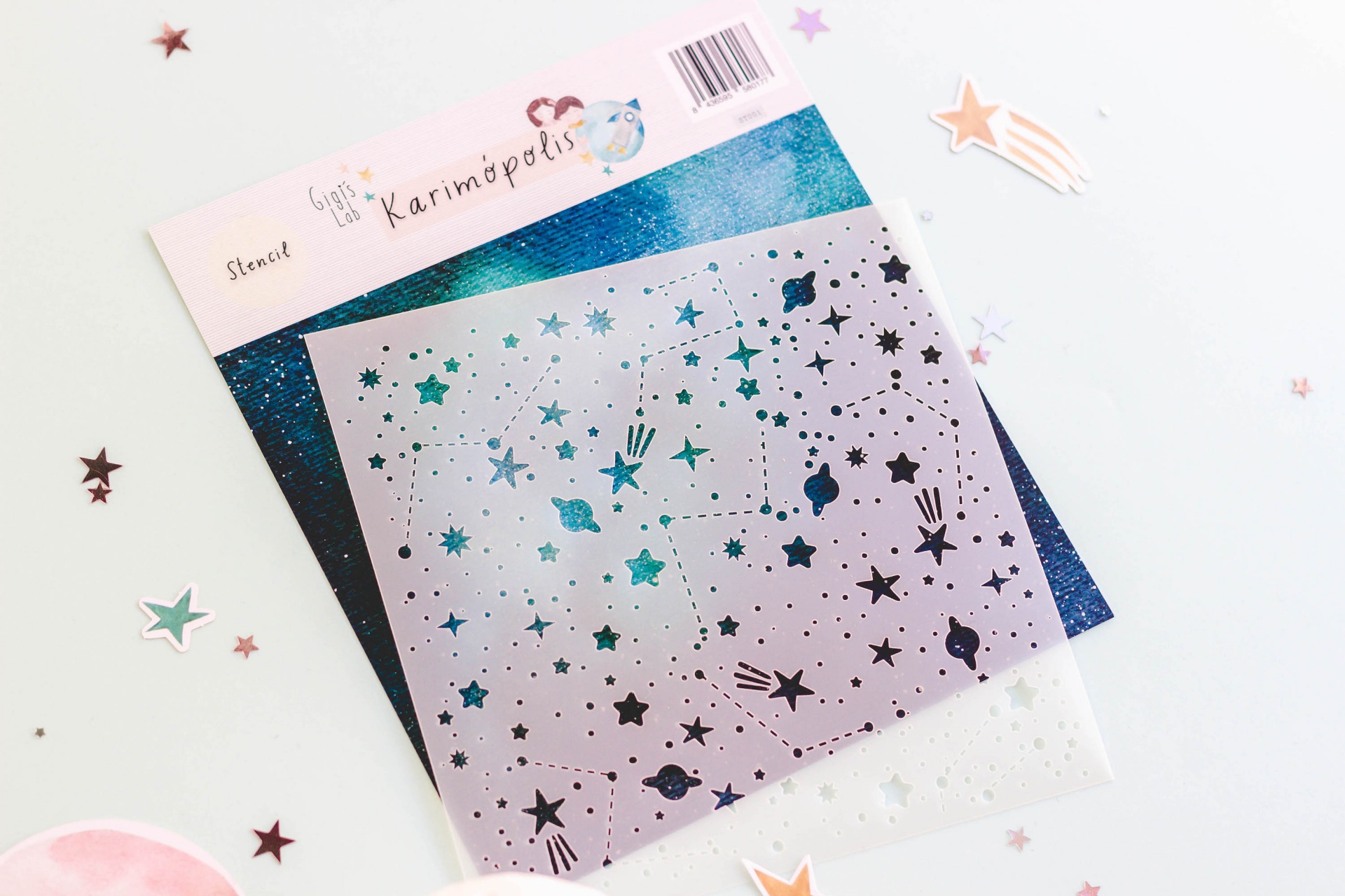 Stencil prateado com padrão de estrelas e planetas sobre fundo brilhante azul e verde