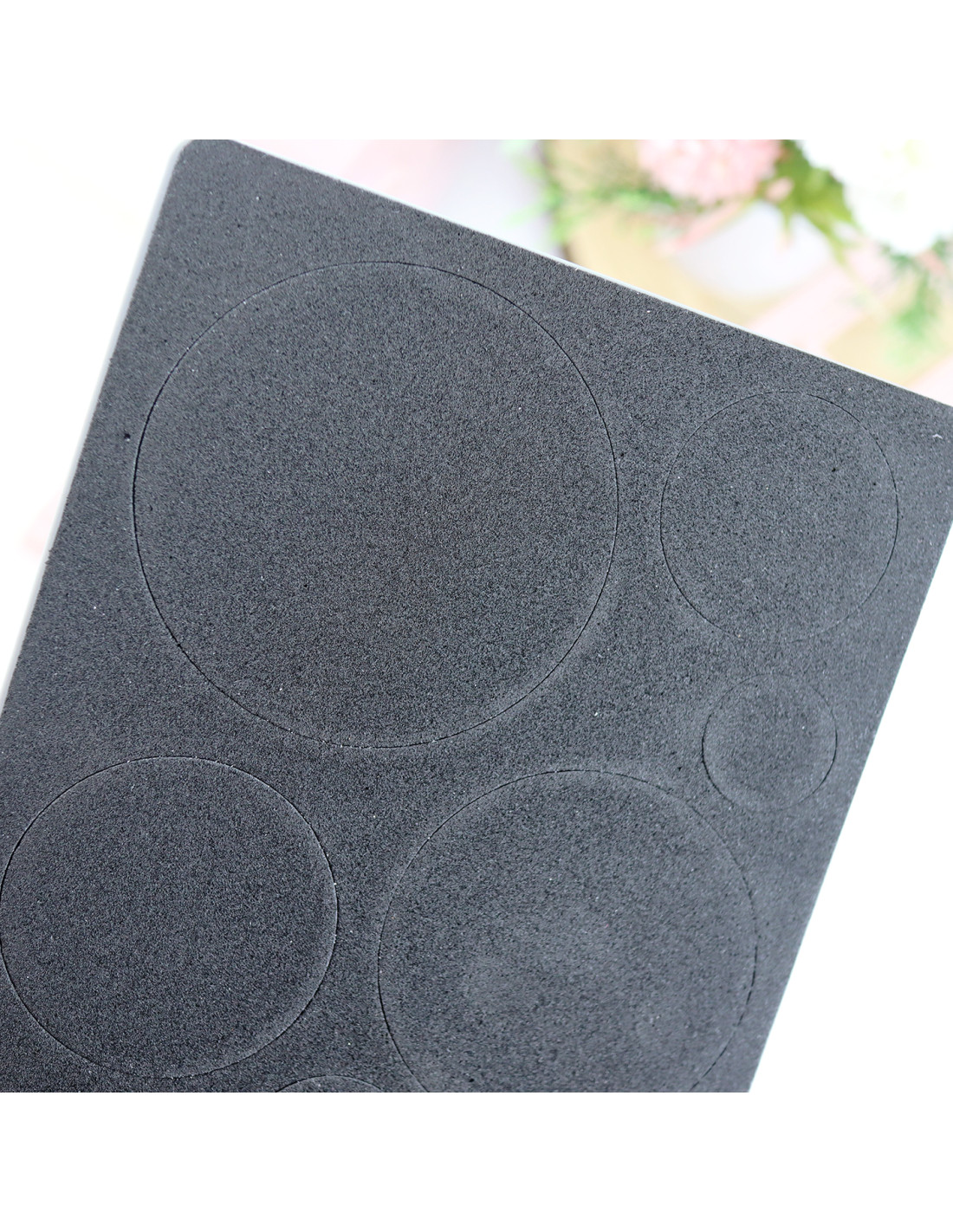 Folha preta com círculos recortados em material tipo borracha ou espuma