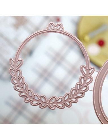 Aro de metal rosa claro com padrão de folhas recortadas em fundo desfocado