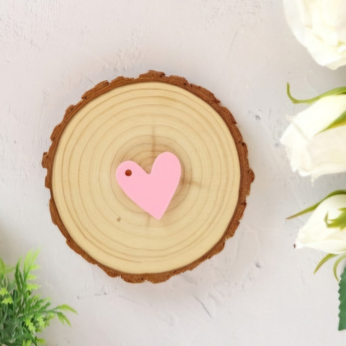 Disco de madeira com coração rosa no centro e flores ao redor