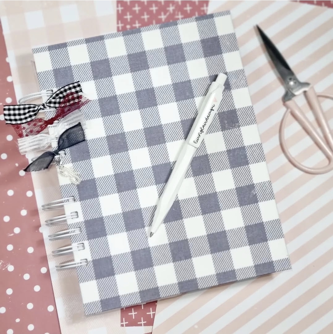 caderno às quadrículas com caneta branca e tesoura rosa