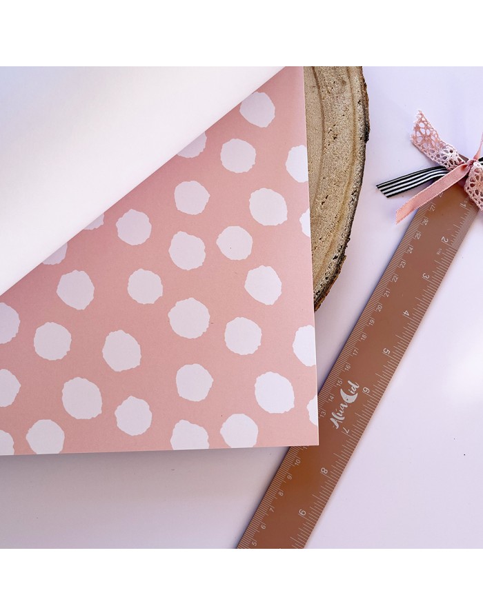 Papel rosa com padrões brancos e régua castanha com fita cor-de-rosa