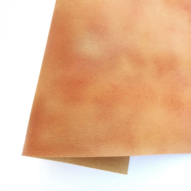 Folha de couro sintético castanho claro com textura fina sobre fundo branco