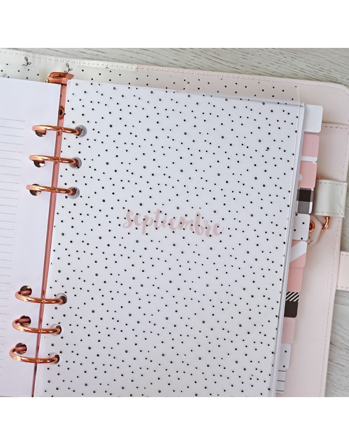 Agenda ou planner com capa branca e pontos pretos sobre superfície de madeira clara