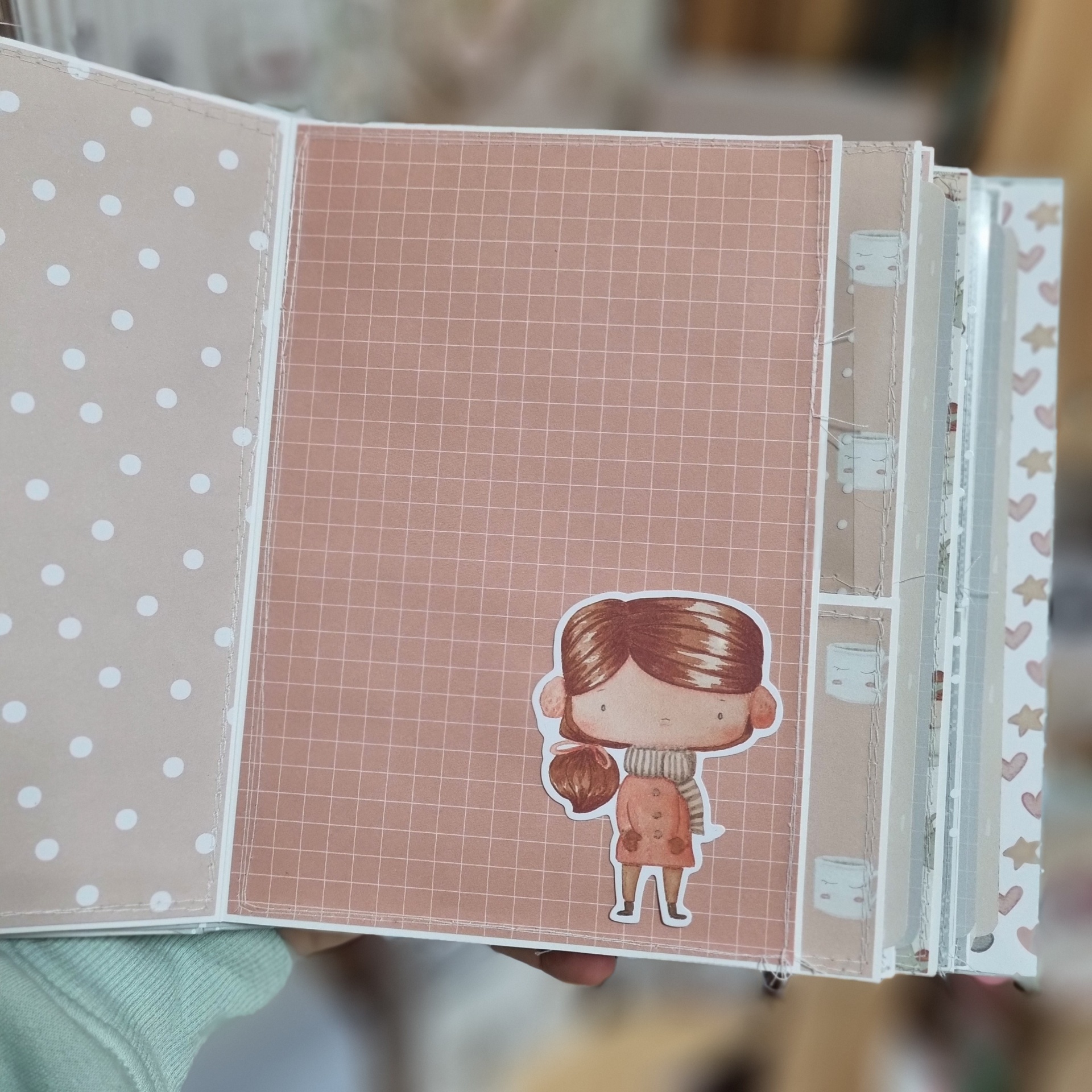 Livro ou álbum de papel artesanal com página decorada por desenho de menina e padrões de bolinhas e quadrados