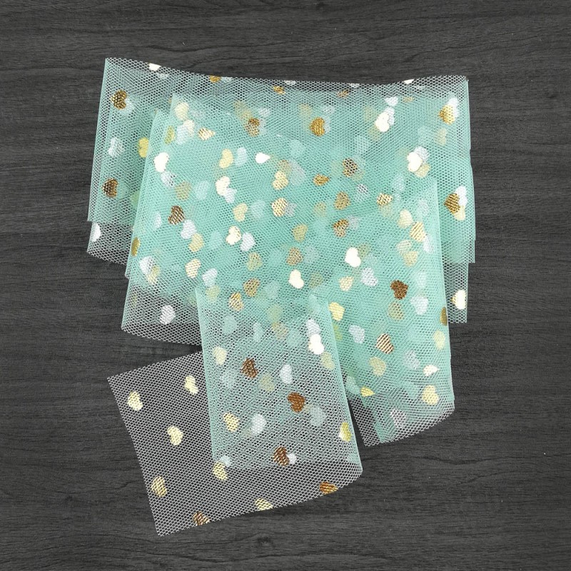 Tecido de tule azul com corações dourados e brancos sobre madeira escura