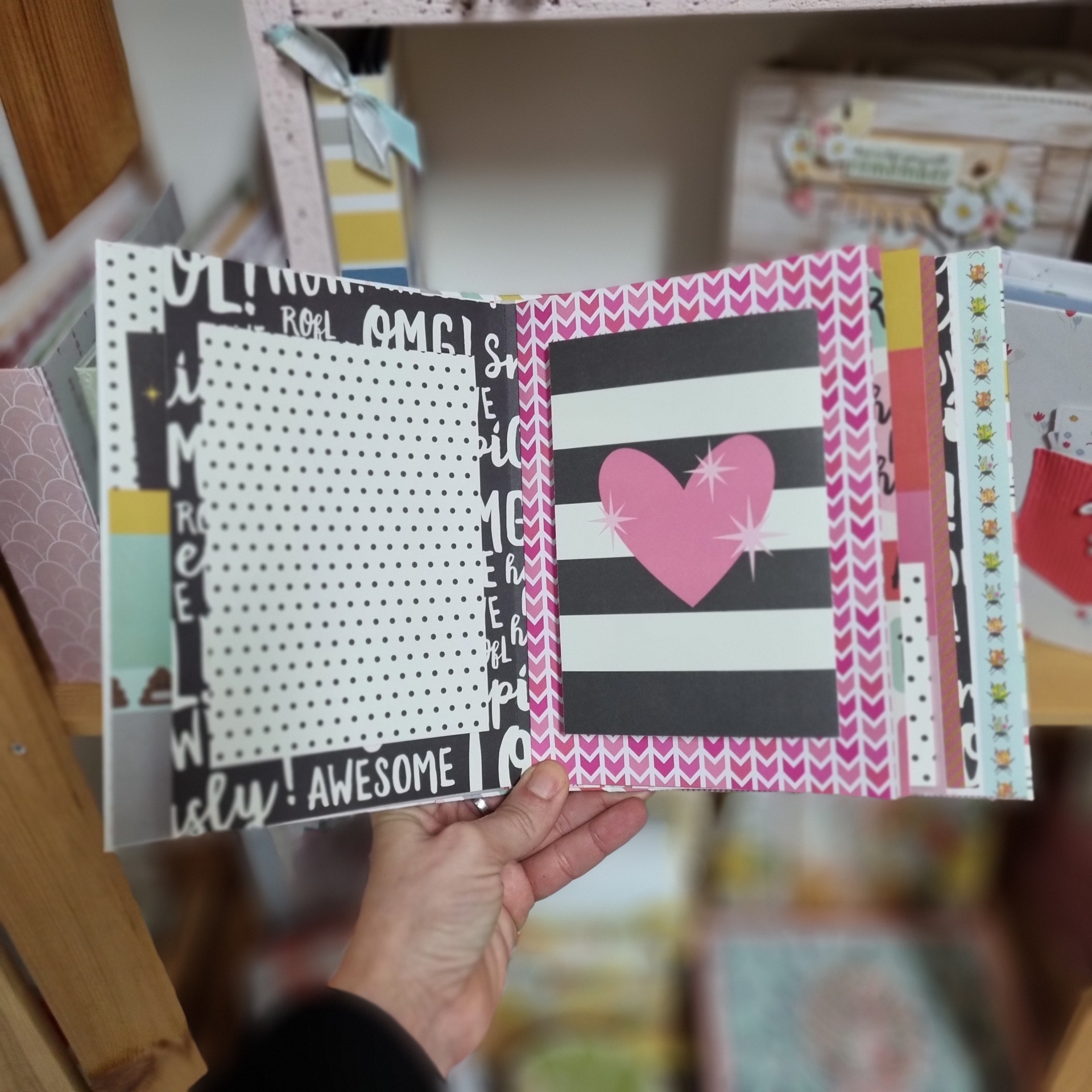 Livro ou álbum decorado a cores vibrantes com padrões e texto, segurado por uma mão