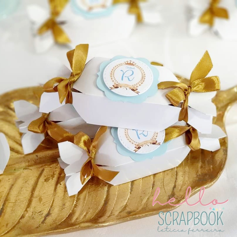 Caixas em forma de bombom com fitas douradas e etiquetas 'R' em prato dourado