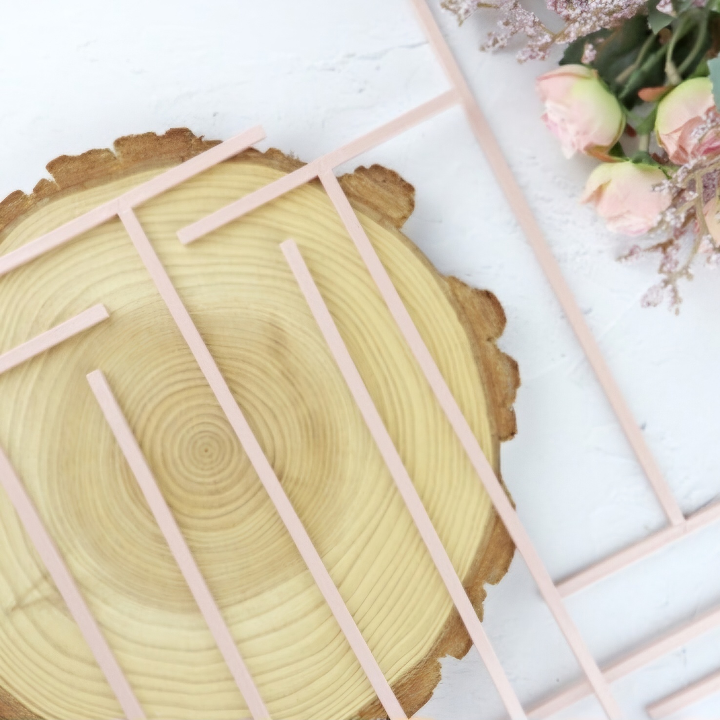 Estrado rosa claro para cama de bonecas sobre madeira com flores ao lado