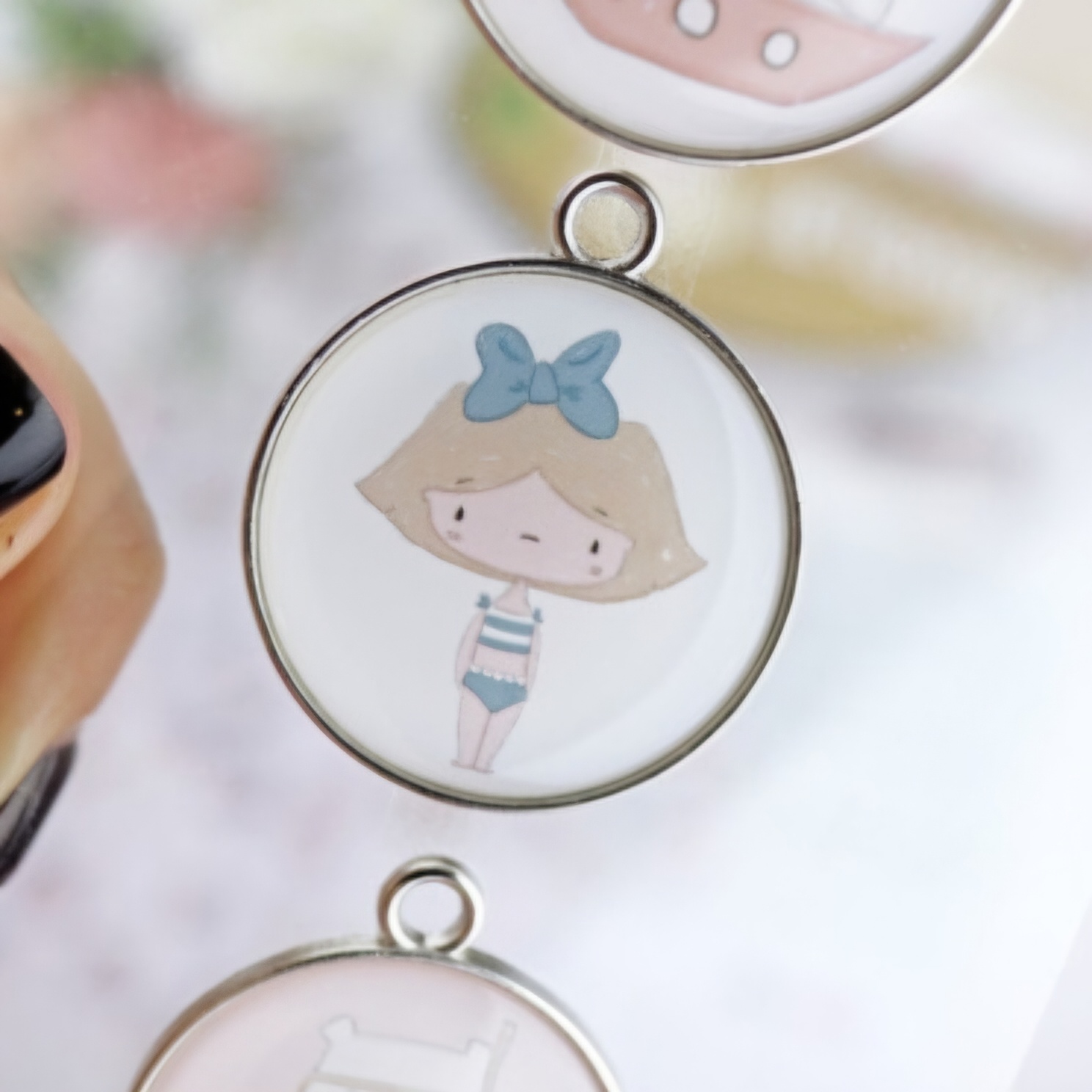 Medalha redonda com desenho de rapariga com laço azul e fato de banho às riscas