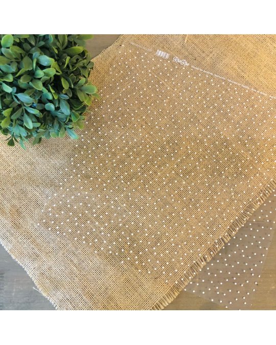 Saco transparente com bolinhas brancas sobre pano de juta com planta verde ao lado