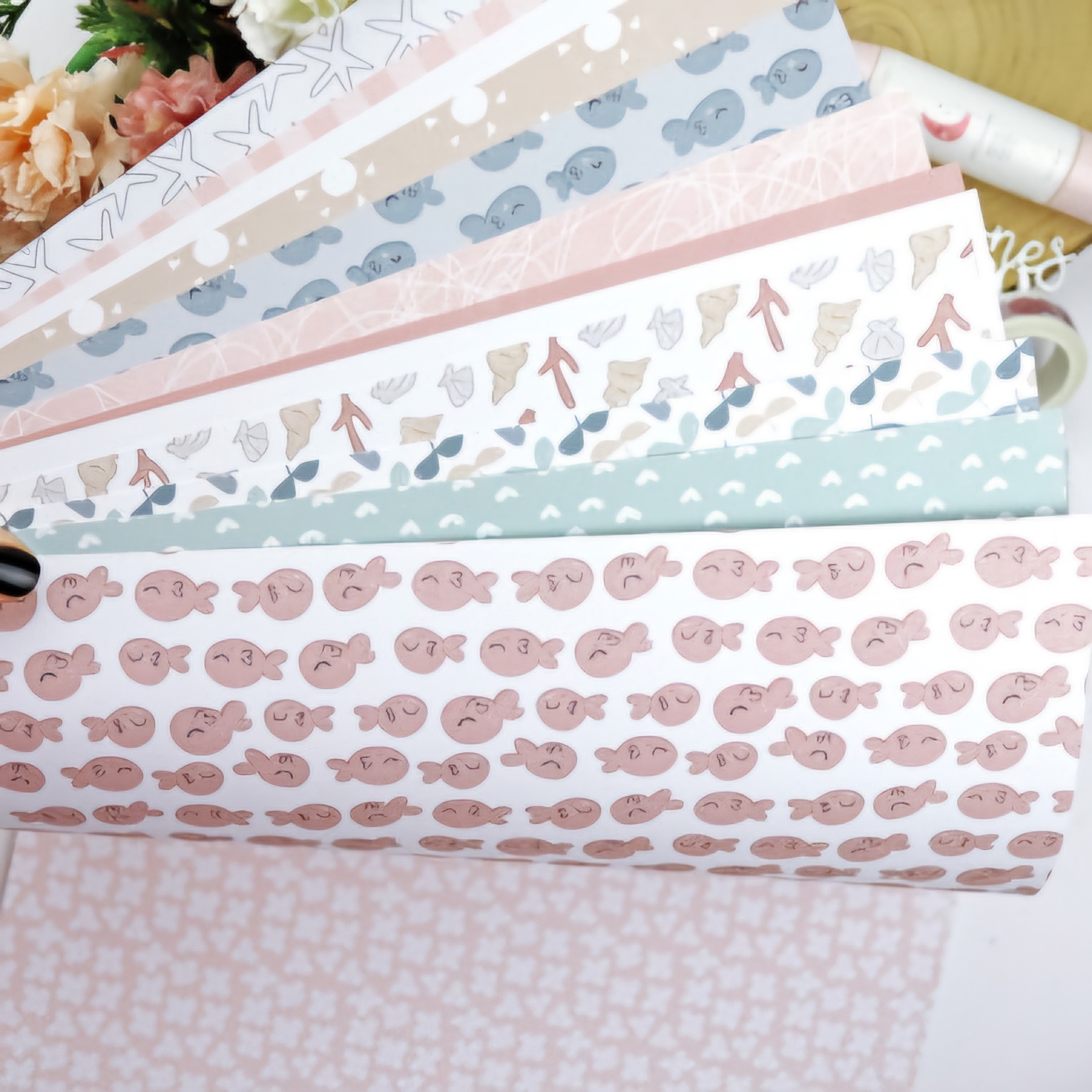 Papéis decorativos com padrões de peixes e conchas em tons pastéis