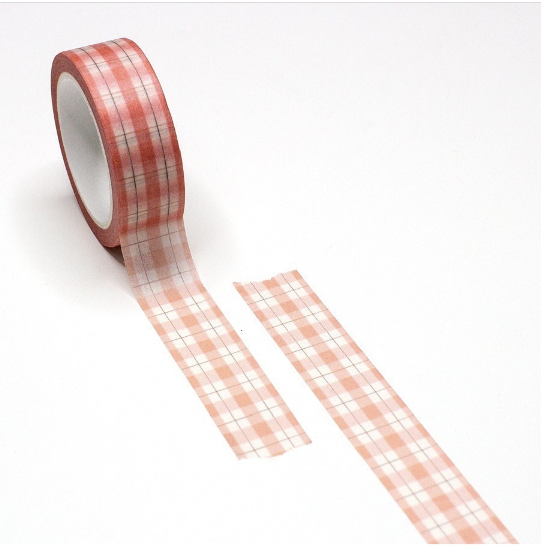 Rolo de fita adesiva com padrão vermelho e branco desenrolado sobre superfície branca