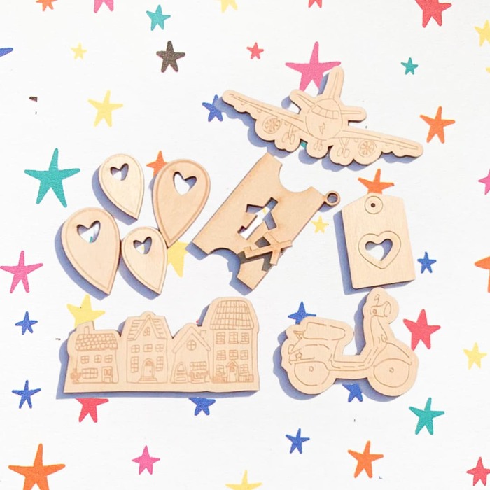 Peças decorativas de madeira com desenhos variados sobre fundo branco com estrelas coloridas